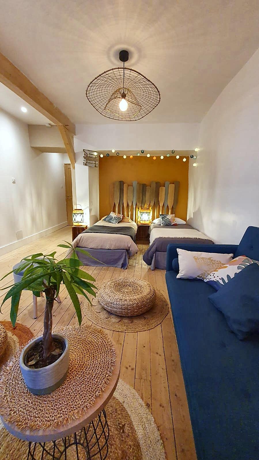 La Mercantine in one long sweep: the blue sofa, the beds and the ochre wall at the far end