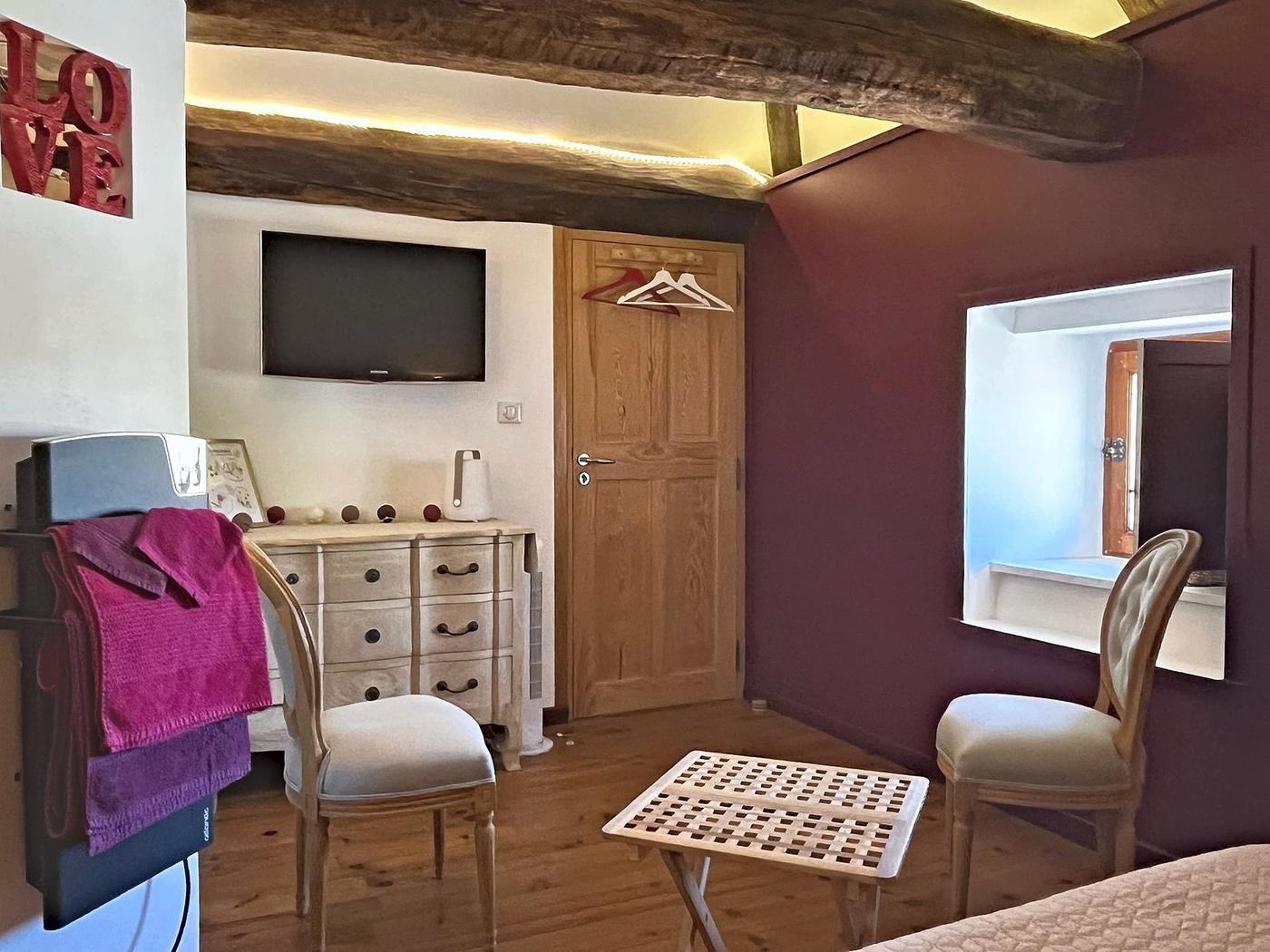 The desk area and television in Le Colombier, with its plum-coloured walls