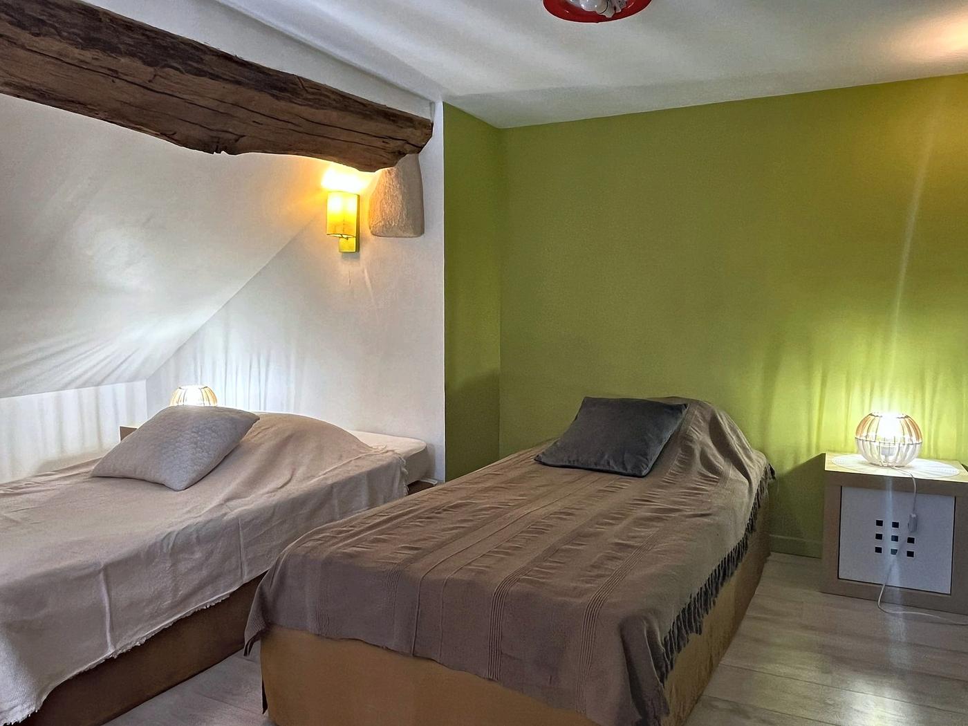 The twin beds in Les Terrasses, against lime-green walls